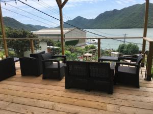 a deck with chairs and tables and a view of the water at Costa Hinase Resort in Kakui-jima