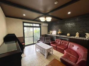a living room with leather furniture and a piano at 丸亀 Sawai 一棟貸し 丸亀駅徒歩 10人まで宿泊可能 駐車場2台有 子供部屋ベビーベッド有 in Marugame
