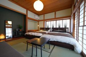 a bedroom with two beds and a table and windows at Hideaway Hakone Sengokuhara in Sengokuhara