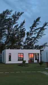 a white house with trees in the background at Vahinn Resort in Fort Dauphin