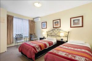 a hotel room with two beds and a window at Knightsbridge Apartments in Melbourne