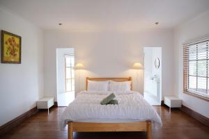 a white bedroom with a large bed with white sheets at Bloom by the Bend in Tooradin
