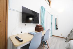 a room with a desk with chairs and a tv on the wall at Mary's Room Sumiyoshi in Sumiyoshi
