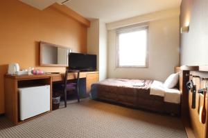 a hotel room with a bed and a desk and a television at ホテルクオーレ敦賀 男性専用の大浴場サウナをご用意 in Tsuruga