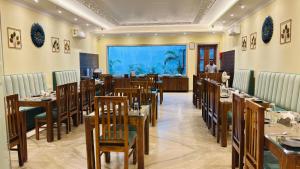 a restaurant with tables and chairs and a man in the background at Amritara Ramila Kutir Ayodhya in Ayodhya