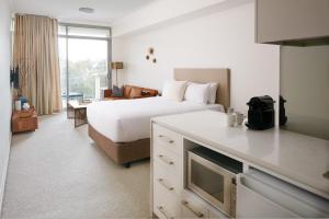 a bedroom with a white bed and a white refrigerator at Nautica Residences Fremantle in Fremantle