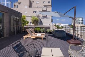 een patio met stoelen en een parasol op een balkon bij Florentin House in Tel Aviv