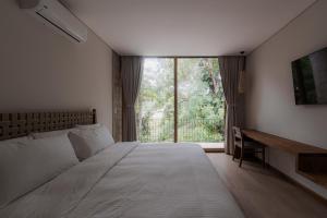 a bedroom with a bed and a desk and a window at The Town at Praia in Jacó +125 photos