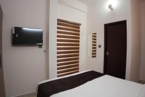 a bedroom with a bed and a television on the wall at Pearl Suites in Cochin +16 photos