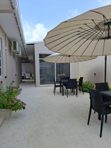 a patio with tables and chairs and an umbrella at Villaasa in Shaviyani Atoll