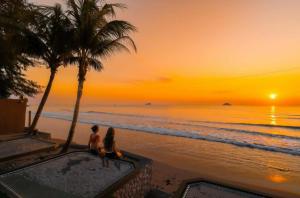two people sitting on the beach watching the sunset at Skippers beach guesthouse in Hua Hin