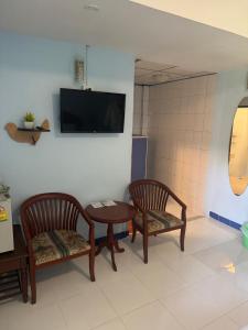 a room with two chairs and a table and a tv at Skippers beach guesthouse in Hua Hin