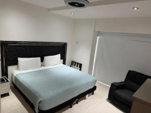 a bedroom with a bed and a black chair at Acapulco Diamante Departamento Olimpya in Acapulco +24 photos
