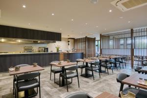 a restaurant with tables and chairs and a kitchen at Aso Hotel in Aso