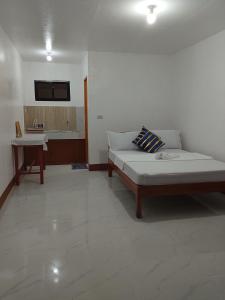 a white room with a bed and a table at Mangas Residents in El Nido