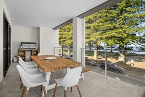 a dining room with a wooden table and white chairs at Harborview Modern Apartment 8F in Victor Harbor