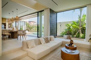 a living room with a white couch and a large window at Kono Villas & Resort in Ungasan