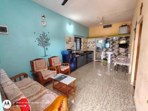 a living room with a couch and chairs and a kitchen at D'Souza Home stay in Māvalli