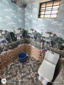 a bathroom with a toilet with a painting on the wall at D'Souza Home stay in Māvalli +19 photos