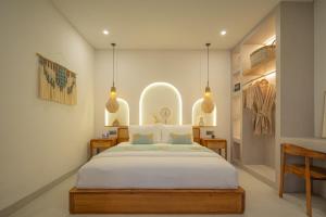 a bedroom with a large white bed and some lights at Monstera Uluwatu in Uluwatu +46 photos