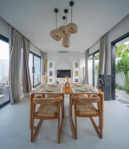 a dining room with a wooden table and chairs at Monstera Uluwatu in Uluwatu