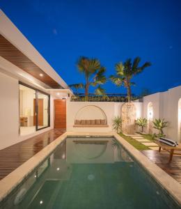 a swimming pool in a house with palm trees at Monstera Uluwatu in Uluwatu