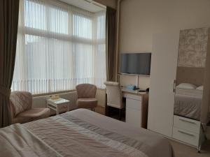 ein Hotelzimmer mit Bett, Schreibtisch und Fernseher in der Unterkunft Hotel Excelsior in Den Haag