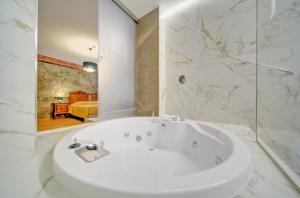 a white bath tub in a bathroom with a bedroom at Liberty Hotel in Turin +88 photos