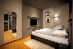 um quarto com uma cama com almofadas brancas e uma televisão em Gateway Budapest Centrum em Budapeste