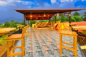 a patio with wooden benches and tables and a pavilion at Aavaas Farm Hostel in Gangāpur