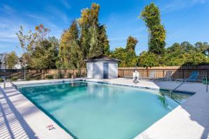a swimming pool with a fence and trees at Spark By Hilton Wilmington in Wilmington