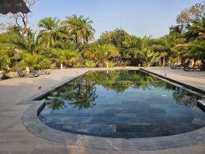 a swimming pool in a resort with palm trees at Camping Casamance in Ziguinchor