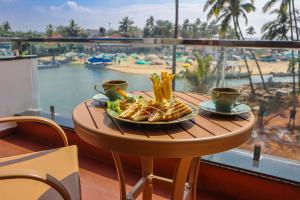 a table with a plate of food and two cups of coffee at River Deck Baga Beach Front in Calangute