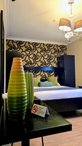 ein Zimmer mit einem Bett und einem Tisch mit grünen Vasen in der Unterkunft Belrom Hotel in Sint-Truiden