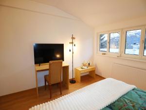 a bedroom with a bed and a desk with a television at Holiday apartment in Bregenzerwald in Sibratsgfäll