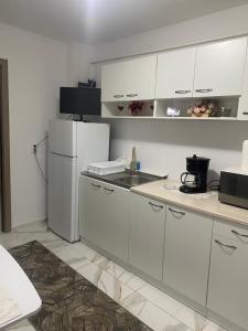 a kitchen with white cabinets and a white refrigerator at Lemora Apartments 1 in Focşani