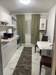 a kitchen with white cabinets and a table and a table and chairs at Lemora Apartments 1 in Focşani