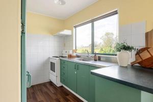 a kitchen with green cabinets and a large window at Peaceful Country Escape in Gordonton - Green Meadows Cottage in Taupiri