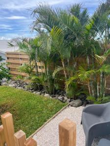 a garden with palm trees and a wooden fence at Case Ylang Blossom in Étang-Salé