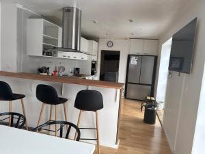 a kitchen with white cabinets and black stools at Kilimanjaro & Stayover in Svinninge