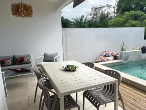 a white table and chairs on a patio with a pool at Case Ylang Blossom in Étang-Salé