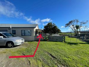 a car parked in a yard next to a house at Self check-in sleepout with bathroom in Te Miro