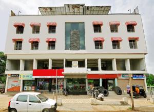 a white building with a car parked in front of it at Hotel Magnum Inn in Junagadh
