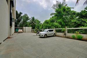 un pequeño coche blanco aparcado en un estacionamiento en Hotel Magnum Inn, en Junagadh