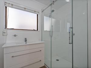 a white bathroom with a sink and a shower at Beachfront Beauty - Whangamata Beachfront Home in Whangamata +18 photos
