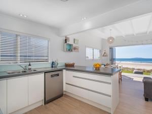 a kitchen with white cabinets and a view of the ocean at Beachfront Beauty - Whangamata Beachfront Home in Whangamata