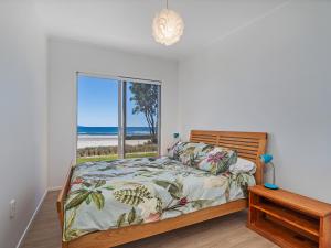 a bedroom with a bed with a view of the beach at Beachfront Beauty - Whangamata Beachfront Home in Whangamata