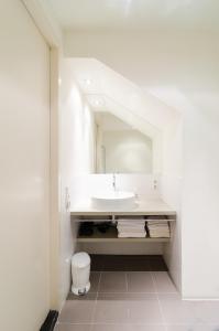 ein weißes Badezimmer mit einem Waschbecken und einem Spiegel in der Unterkunft Marnix Design: Downtown Dream in Amsterdam
