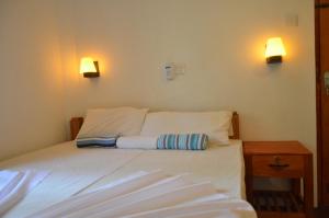 a bed in a room with two lights on the wall at Yaye Guest House in Tissamaharama