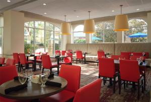 a restaurant with red chairs and tables and windows at Hilton Garden Inn Jackson-Madison in Madison